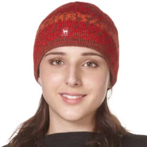 Portrait einer lächelnden Person mit einem roten Strickmütze, die ein dezent gemustertes Design hat.