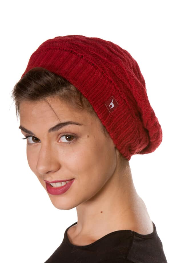 Frau mit einem roten Strickbeanie, die nach vorne schaut und lächelt.
