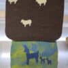 Filzstücke; ein braunes mit weißen Schafen und ein blau-grünes mit blauen Tiermotiven.