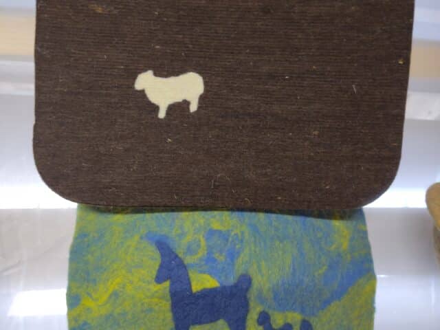 Filzstücke; ein braunes mit weißen Schafen und ein blau-grünes mit blauen Tiermotiven.