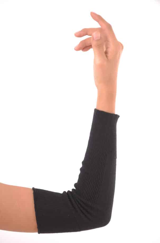 Eine Hand, die einen schwarzen gestrickten Armwärmer trägt, vor einem weißen Hintergrund.