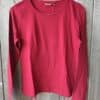 Ein rotes Langarmshirt in Größe S hängt an einem blauen Kleiderbügel vor einem Holzhintergrund.
