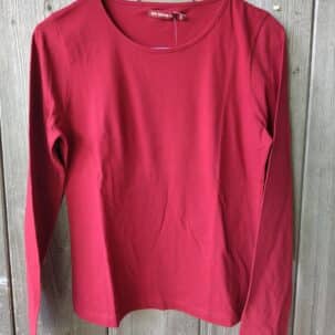 Ein rotes Langarmshirt in Größe S hängt an einem blauen Kleiderbügel vor einem Holzhintergrund.