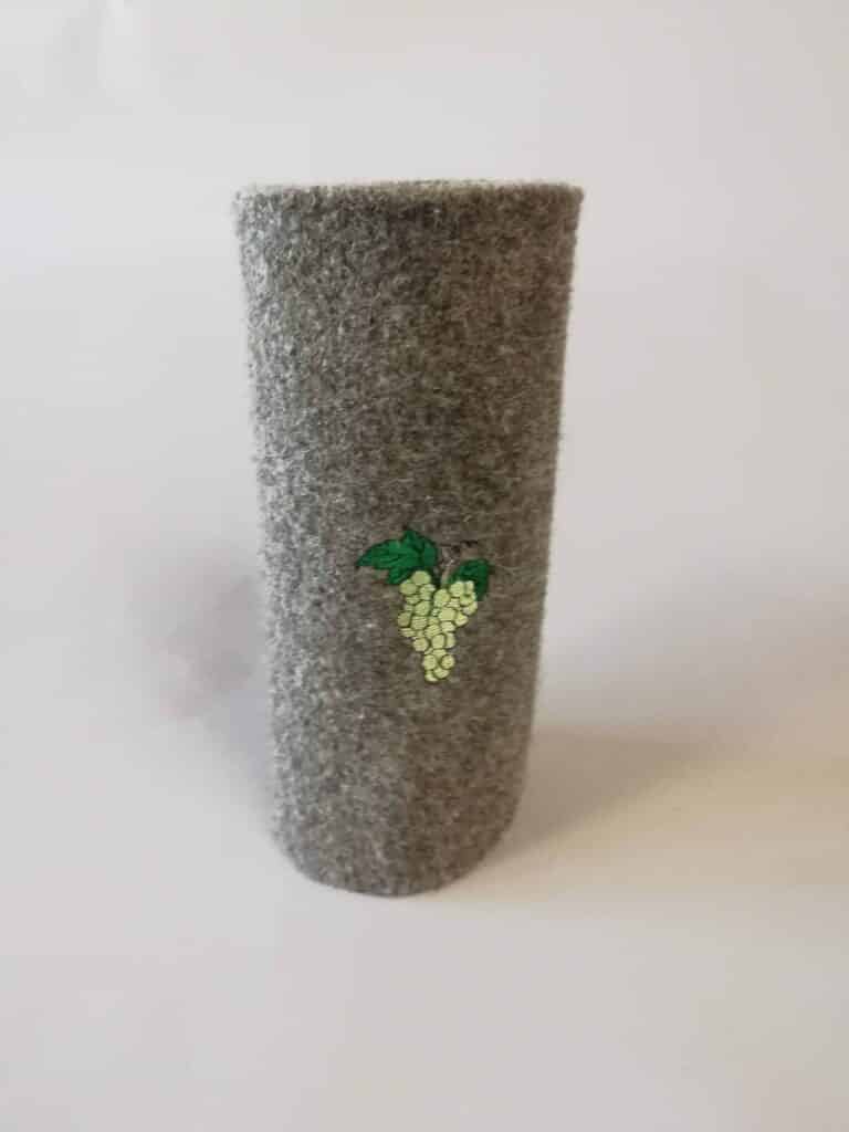 Graues Filz-Thermobehältnis mit einem aufgestickten Motiv aus weißen Trauben und grünen Blättern auf der Vorderseite.