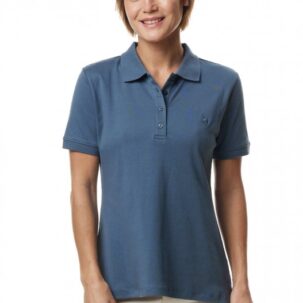 Frau in blauem Polohemd und weißer Hose vor weißem Hintergrund.