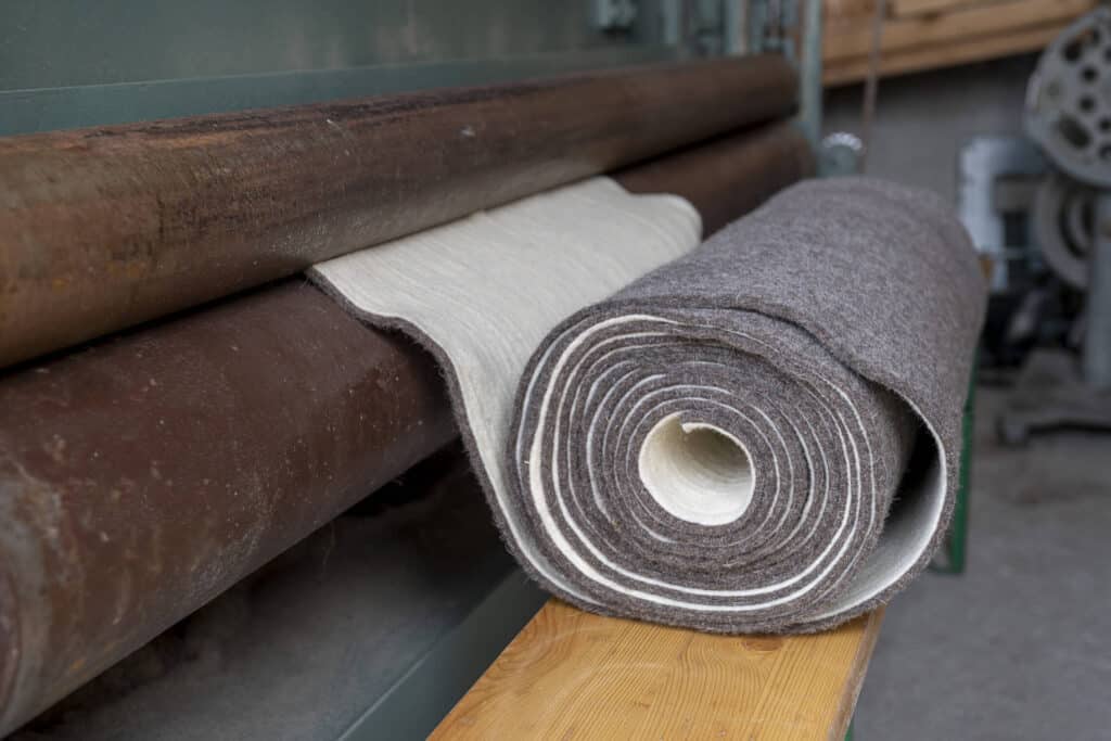 Rolle aus Filz auf Tisch neben einer alten Maschine.