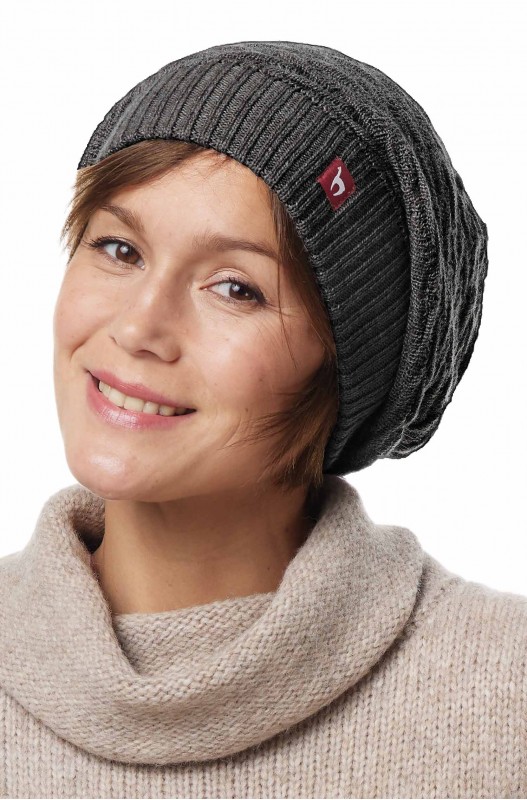 Frau mit grauer Strickmütze und beigem Rollkragenpullover lächelt.