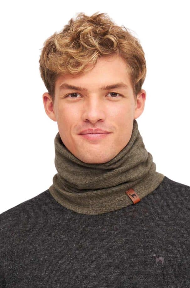 Mann mit lockigem, blondem Haar trägt einen olivfarbenen Schlauchschal und einen dunkelgrauen Pullover.