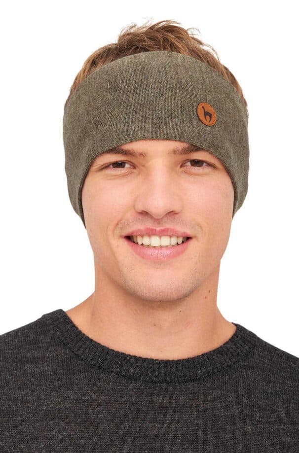 Ein lächelnder Mann trägt ein graues Stirnband mit einem kleinen runden Lederlogo darauf, kombiniert mit einem dunkelgrauen Pullover.