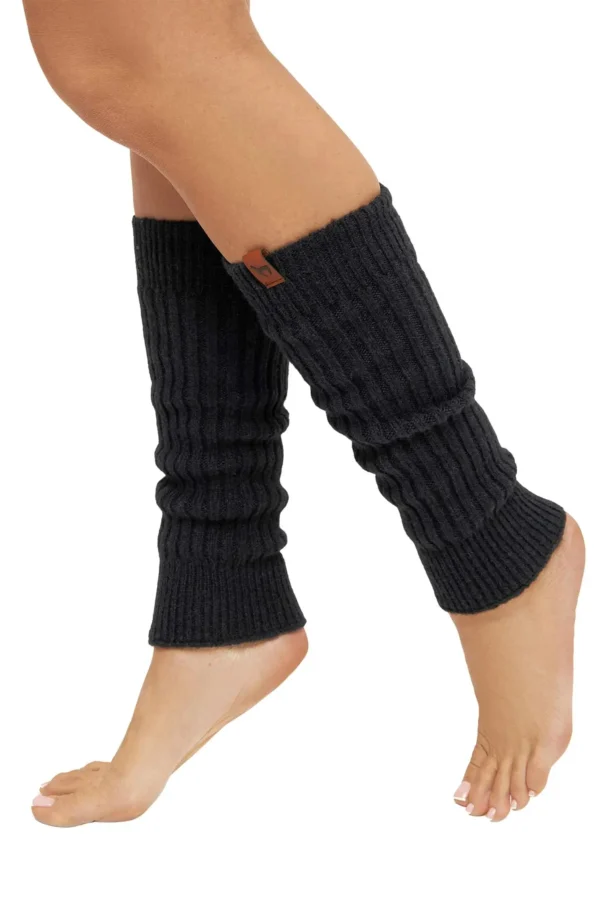 Ein Paar Beine in schwarzen gestrickten Beinstulpen, die bis über die Fesseln reichen; die Person steht auf den Zehenspitzen.