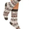 Beine, die gestrickte Socken mit geometrischen Mustern in Braun- und Grautönen tragen, auf weißem Hintergrund.