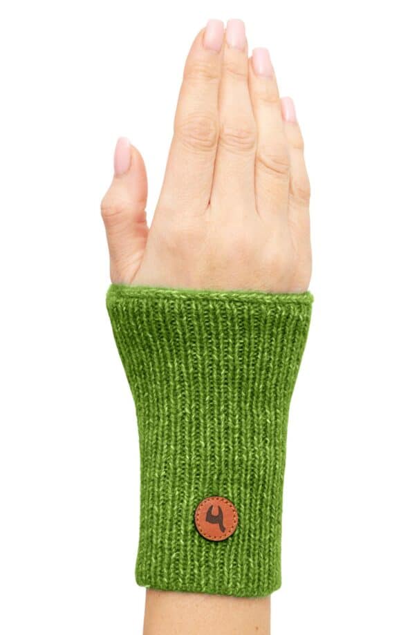 Eine Hand trägt einen grünen gestrickten Handwärmer mit einem kleinen braunen Lederetikett mit Logo am Handgelenk.