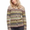 Frau mit blondem Haar trägt einen gemusterten Strickpullover mit Knöpfen und schwarzen Jeans.